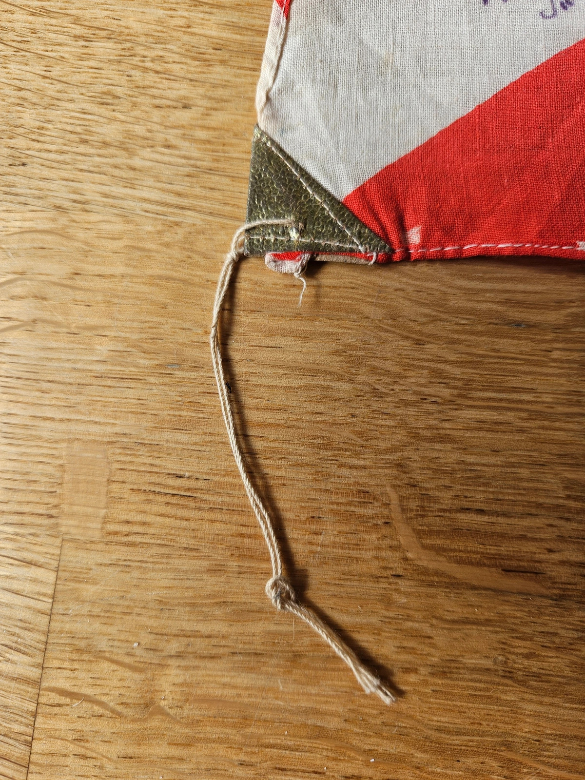 Hoist corner with green textured reinforcement tab and cotton tie line (detail).