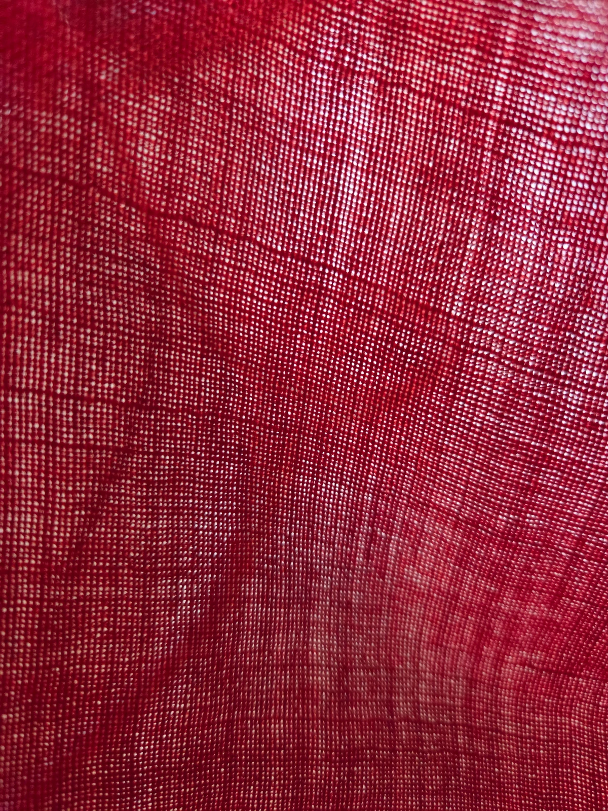 Macro shot through the red bunting showing the open, coarse weave of the wool.