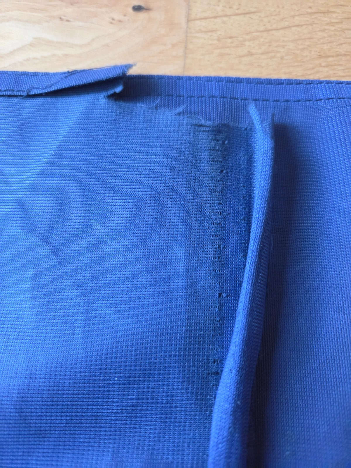 Fly-end corner with longitudinal tear through the hem