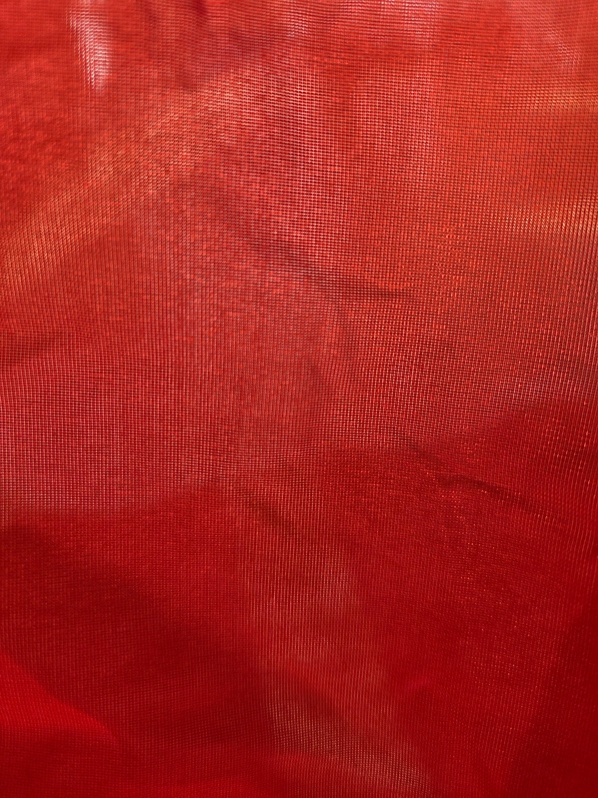 Transmitted-light view of red synthetic flag cloth
